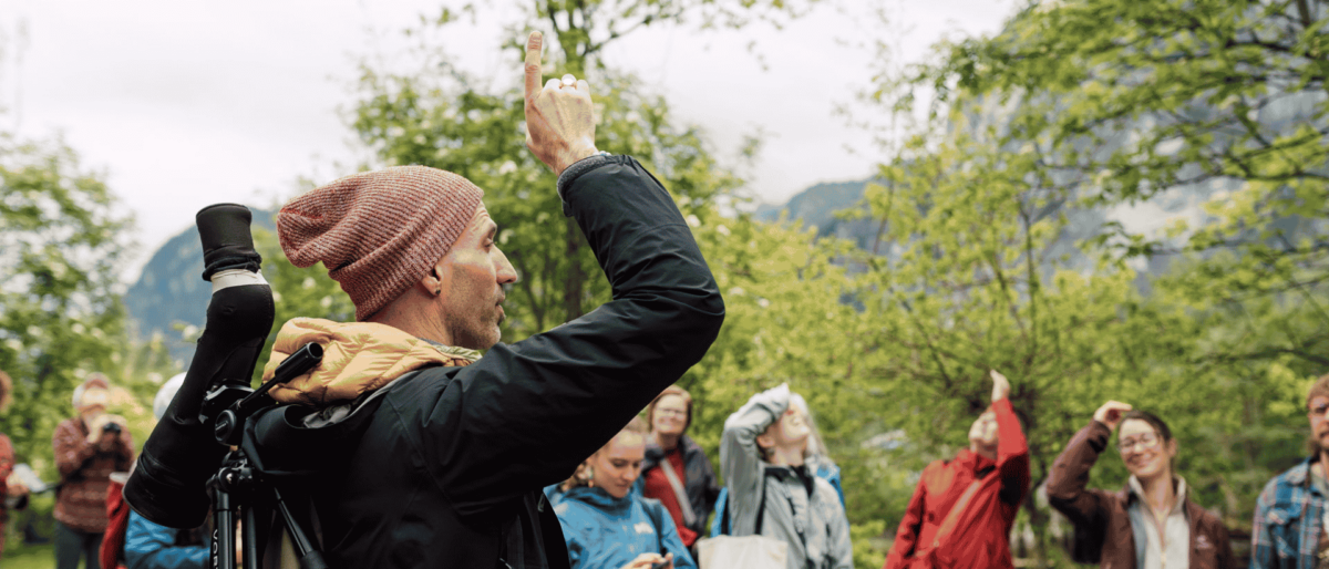 Group of people on a guided bird walk, one of the people is pointing in the air,