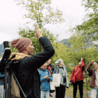 Group of people on a guided bird walk, one of the people is pointing in the air,