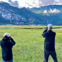 Two people viewing Western purple martins through binoculars in the Squamish Estuary